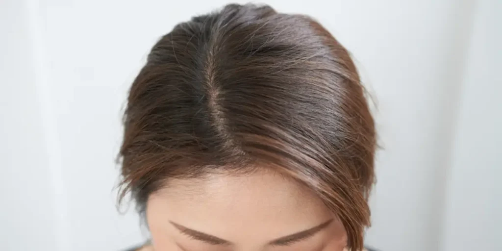 Worried woman checking hairbrush for hair fall, concerned about Female Pattern Baldness at home.