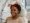 Black woman smiling while receiving Laser Hair Regrowth therapy in a clinic.