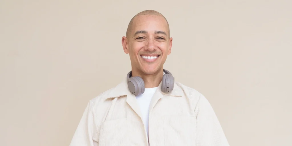 Smiling bald man with headphones, showing natural confidence and results of Mens Hair Systems.
