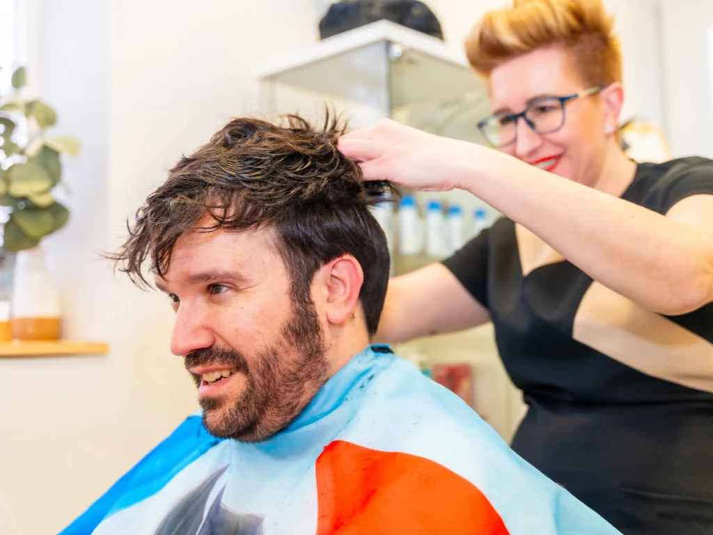 Man with a fitted male hair system getting a haircut for a seamless finish and natural style.