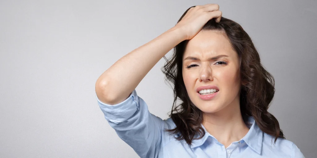 Worried woman touching her scalp, showing discomfort and concerns about Hair loss women UK.