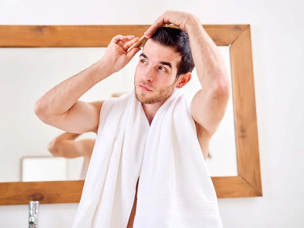 Man checking hair density in mirror as part of regenerative hair loss treatments UK